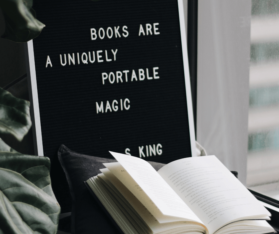Black sign displaying a book quote from author Stephen King with an open book on the table. 